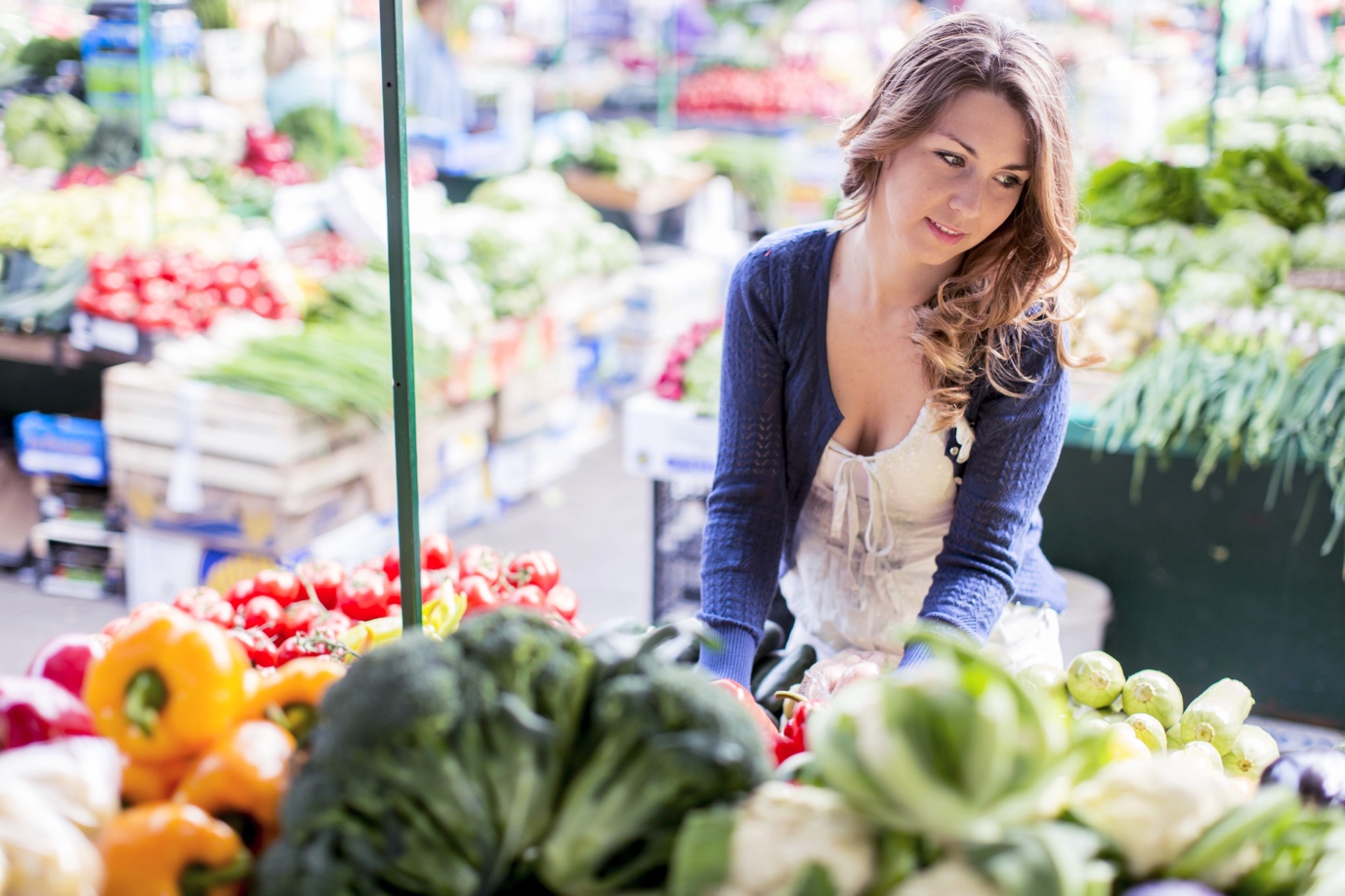 woman perusing vegetables in open market