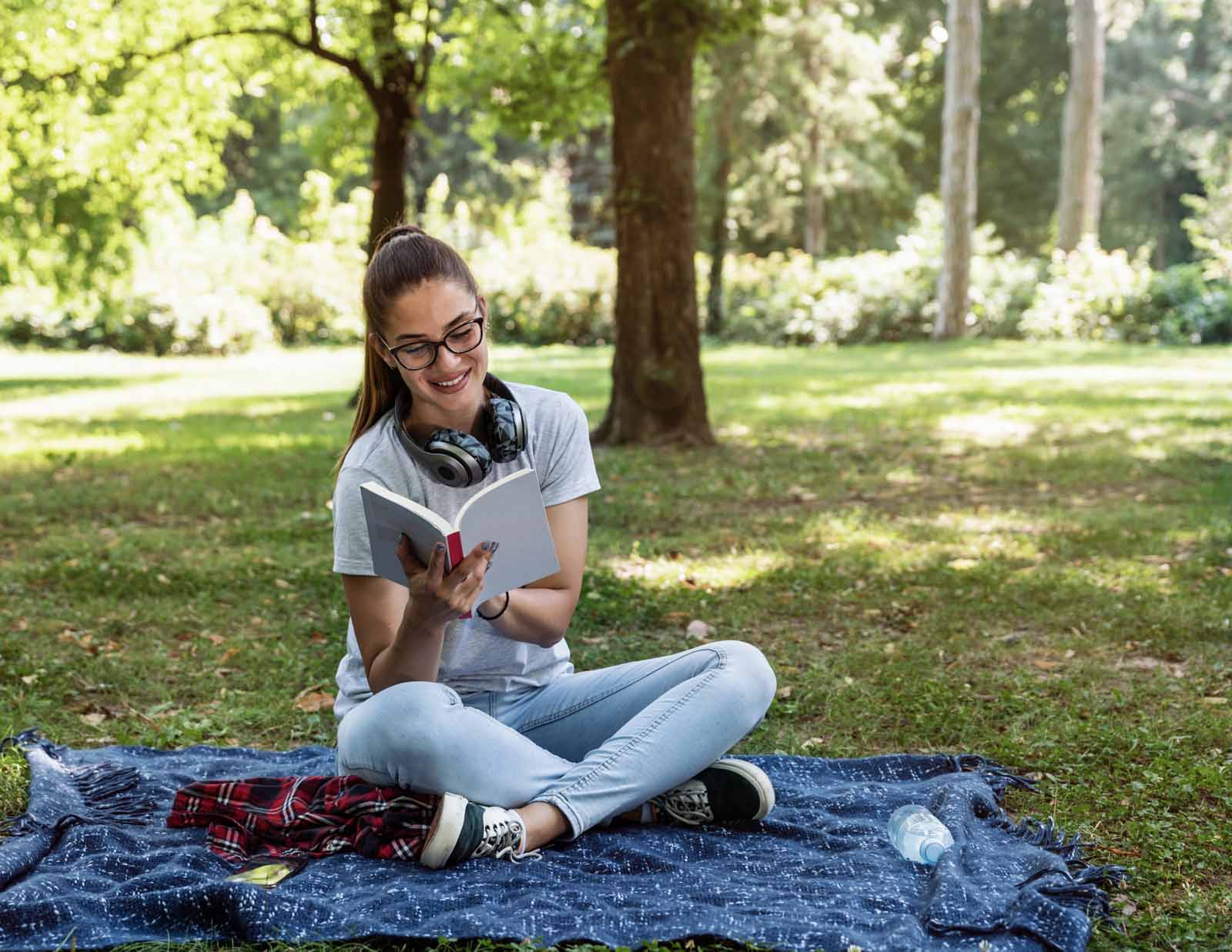 woman reading book on blanket in nature