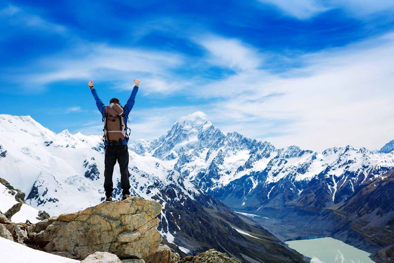 man with arms raised in front of mountain vista